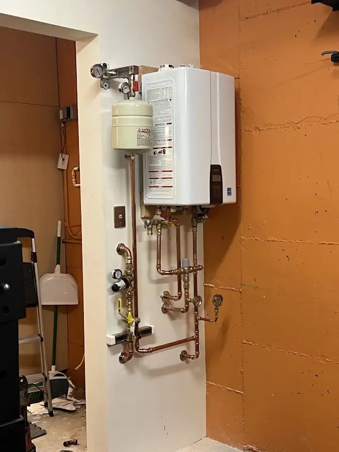 Plumbing technician inspecting water heater connections in Allouez